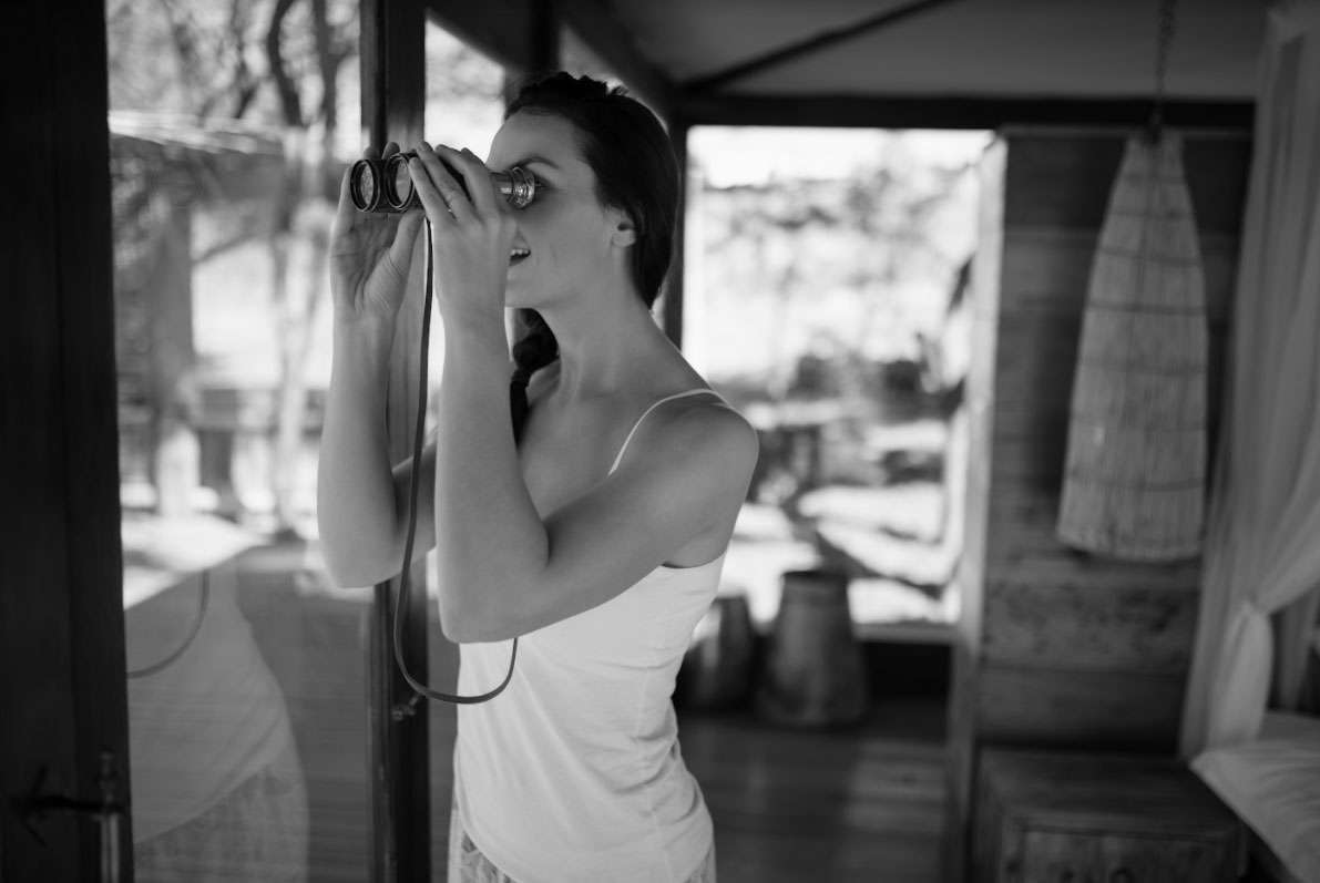 Woman using binoculars to observe her surroundings, indoors, with a focus on marketing strategies and adapting to changes in a post-pandemic environment.