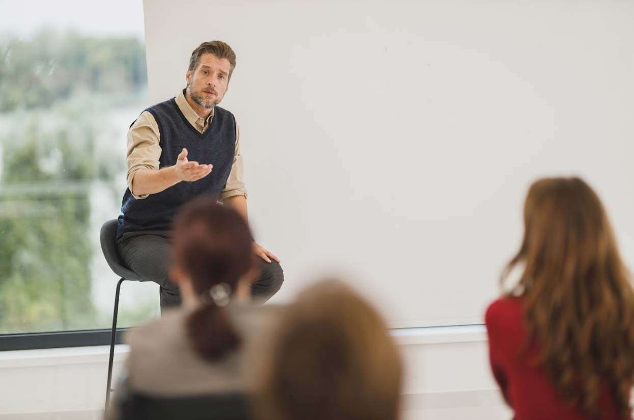 Man speaking to an audience in a modern setting, emphasizing communication strategies for social brand building.