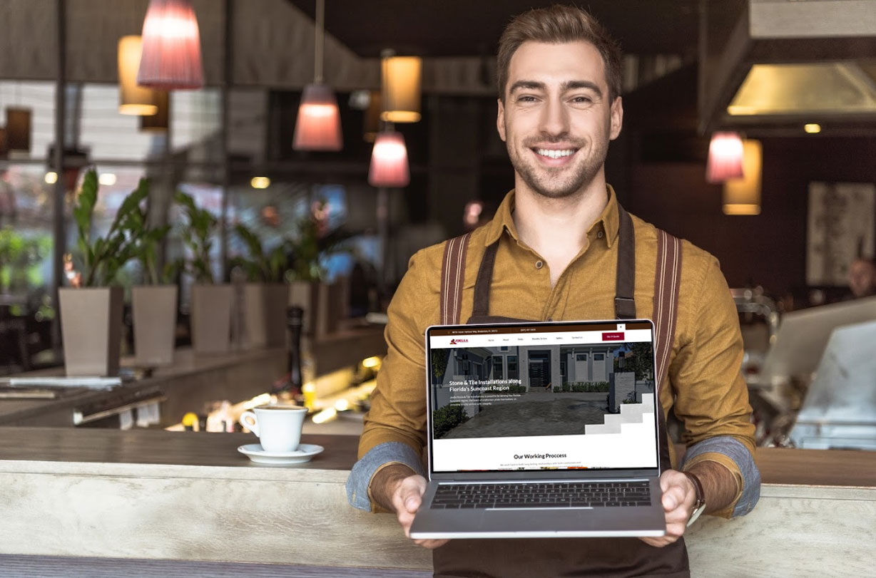 Smiling man in a café holding a laptop displaying a professional website design, emphasizing user experience and digital storefronts for businesses.